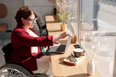 a woman in a wheelchair reading about living with cerebral palsy on a laptop