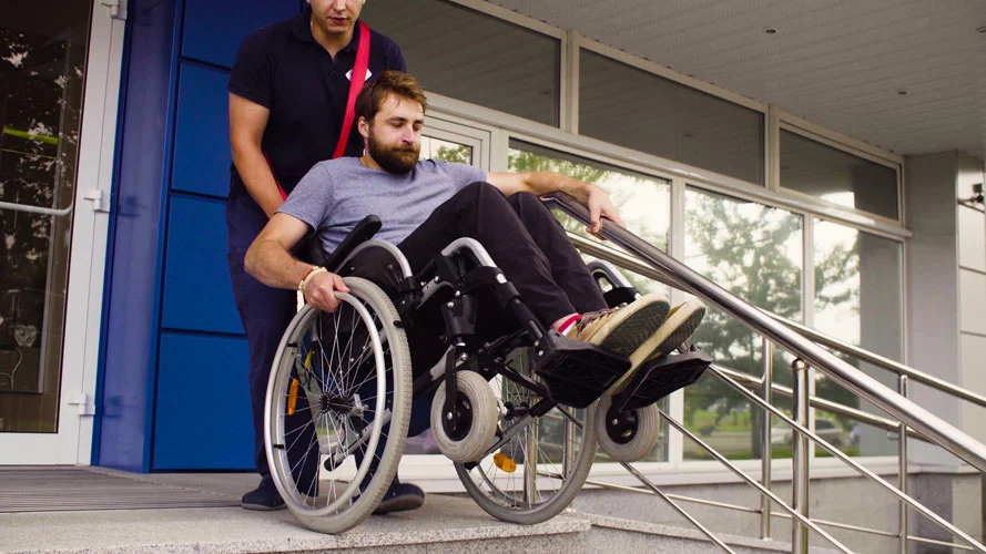 man bringing a disabled person downstairs