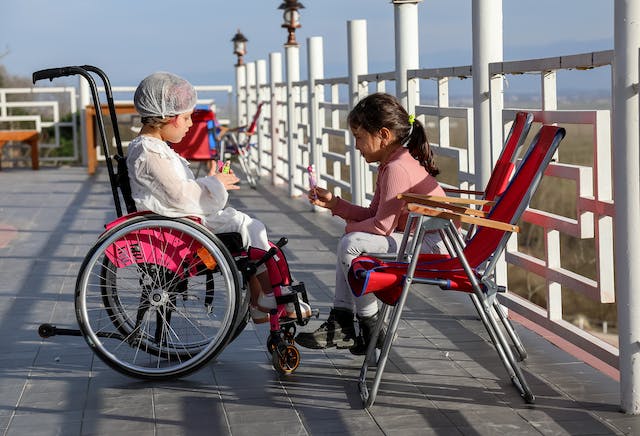 Disabled girl talking to a non-disabled friend to symbolize the impact of standing power chairs